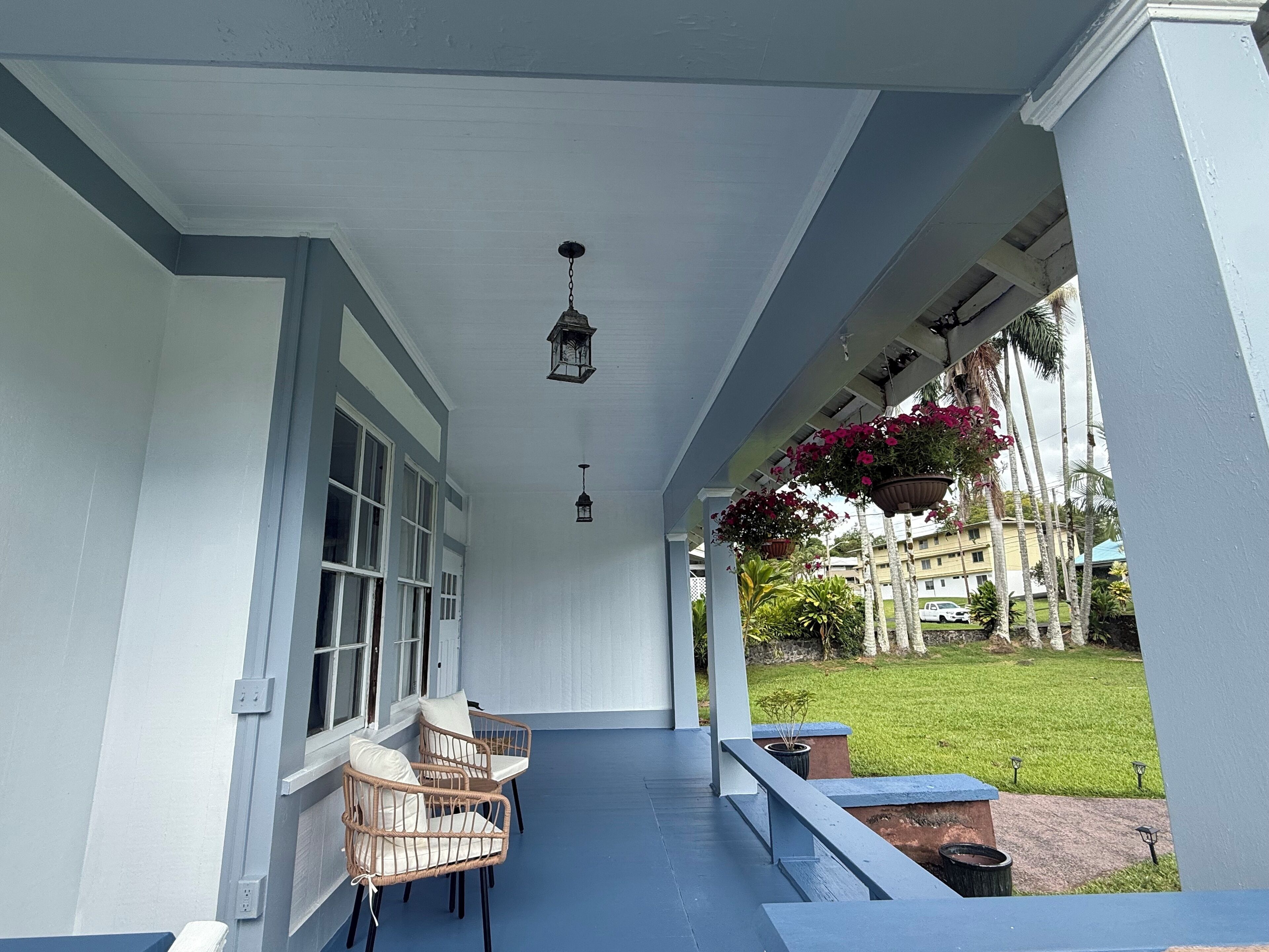 A covered porch with wicker chairs and hanging flower baskets.