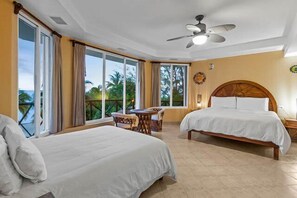 A hotel room with two beds, a dining table, and a view of the outdoors.