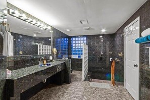 A bathroom with a marble vanity, a large mirror, and a shower area.