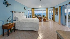 A bedroom with a bed, a nightstand, a chair, and a view of the ocean. - Oceanfront Villa, Private Pool, Great Sunsets (Cozumel)