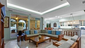 A spacious living area with a large L-shaped sofa, a wooden coffee table, and a kitchen area with a bar counter and stools. - Oceanfront Villa, Private Pool, Great Sunsets (Cozumel)