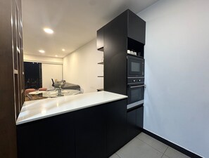 Une cuisine moderne avec un plan de travail blanc, des armoires noires, un four encastré et un four à micro-ondes.