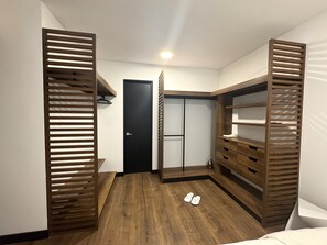 A walk-in closet with wooden shelving, a black door, and a pair of shoes on the floor.