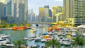 A marina with numerous boats docked, surrounded by high-rise buildings and palm trees. - First Line Canal View Studio w/ Balcony MAX 4 Pax (Dubai Marina)