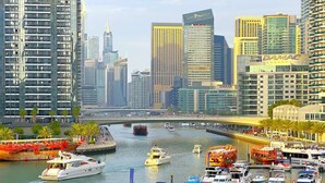 A marina with various boats docked, surrounded by high-rise buildings and palm trees. - First Line Canal View Studio w/ Balcony MAX 4 Pax (Dubai Marina)