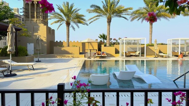 A pool area with lounge chairs and palm trees. - UltraLuxury Flat Amazing Pool Near to Burj Al Arab (Jumeirah Medinat Living)