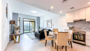 A modern kitchen with a built-in oven and a dining area with a table and chairs. - UltraLuxury Flat Amazing Pool Near to Burj Al Arab (Jumeirah Medinat Living)