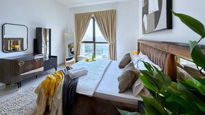Une chambre d’hôtel moderne, dotée d’un grand lit, d’une commode, d’un miroir et offrant une vue sur la ville par la fenêtre.