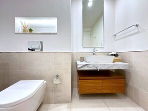 Et moderne badeværelse med toilet, vask og spejl.