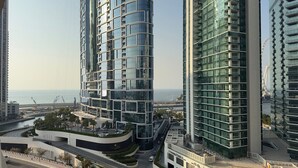 A modern high-rise building with a curved facade, located near a coastal area with a view of the sea. - Opulent Flat with Beach, Pool & Canal View in JBR (Dubai Marina)