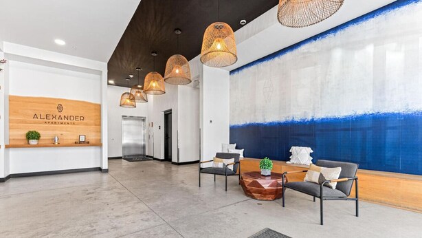 A modern reception area with a wooden reception desk, a blue abstract wall, and a seating area with chairs and a coffee table.