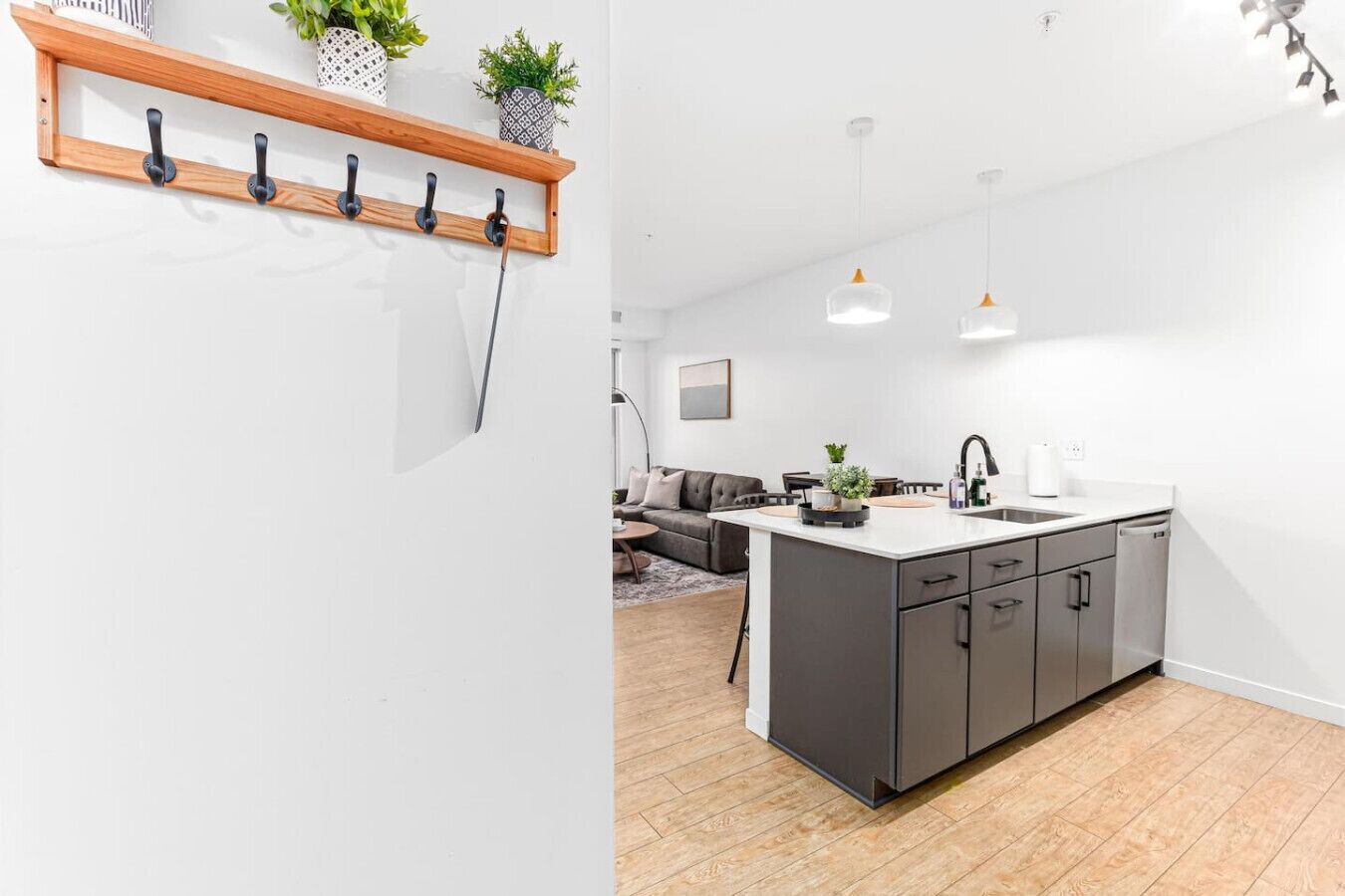 A modern kitchen with a central island, dark cabinetry, and pendant lighting.
