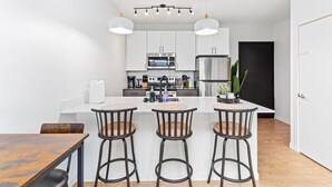 A modern kitchen with white cabinets, stainless steel appliances, and a central island with bar stools.
