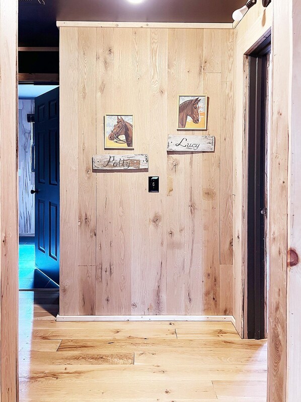 Una puerta de madera con dos placas, una que dice “Polly” y la otra “Lucy”, y dos cuadros con imágenes de caballos encima.