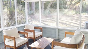 A sunlit room with wooden furniture and large windows overlooking a forested area. - Wicklow Hall (Georgetown)