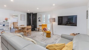 A modern living room with a grey sofa, yellow armchair, and a TV mounted on the wall. - Slow M’Ocean Cabarita - Pet Friendly (Tweed)