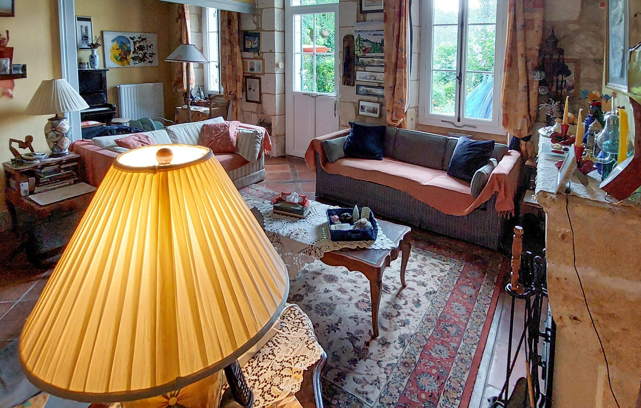 Een gezellige woonkamer met een grote lamp, een bank, een salontafel en een boekenplank.
