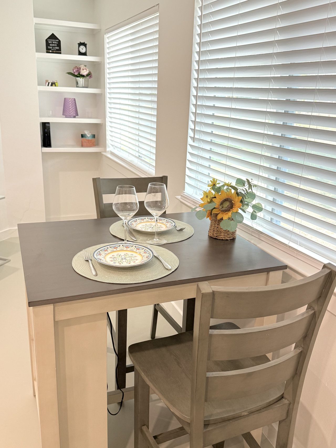 A dining table set with two wine glasses, plates, and a vase with sunflowers.