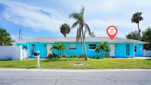 A bright blue house with a mailbox, palm trees, and a clear sky.