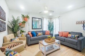 Un salón con un conjunto de sofá, una mesa de centro, un tablero de ajedrez y plantas decorativas.