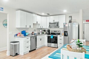 Una cocina moderna con gabinetes blancos, electrodomésticos de acero inoxidable y una decoración azul y blanca.