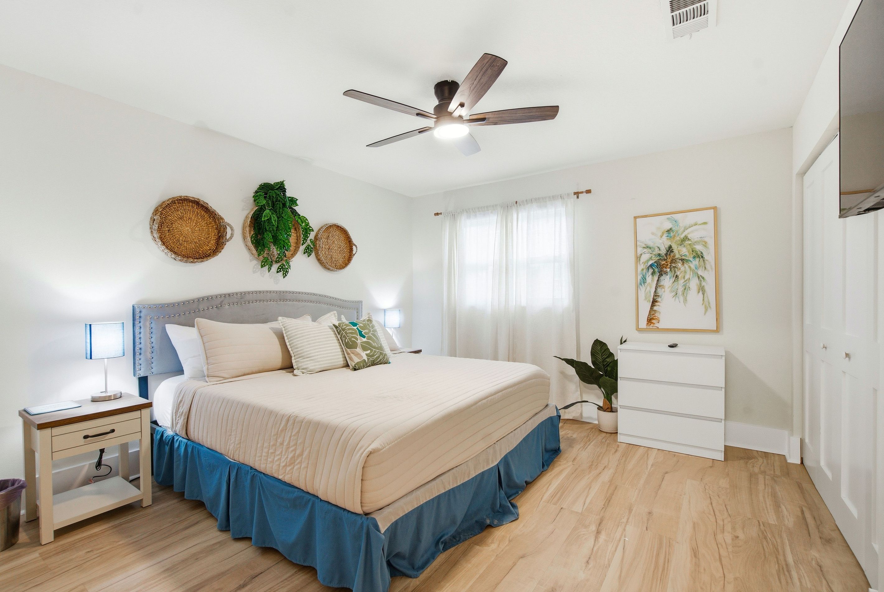 A bedroom with a bed, bedside tables, a ceiling fan, and a window with curtains.