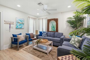 A modern living room with a sofa set, a coffee table, and a ceiling fan.