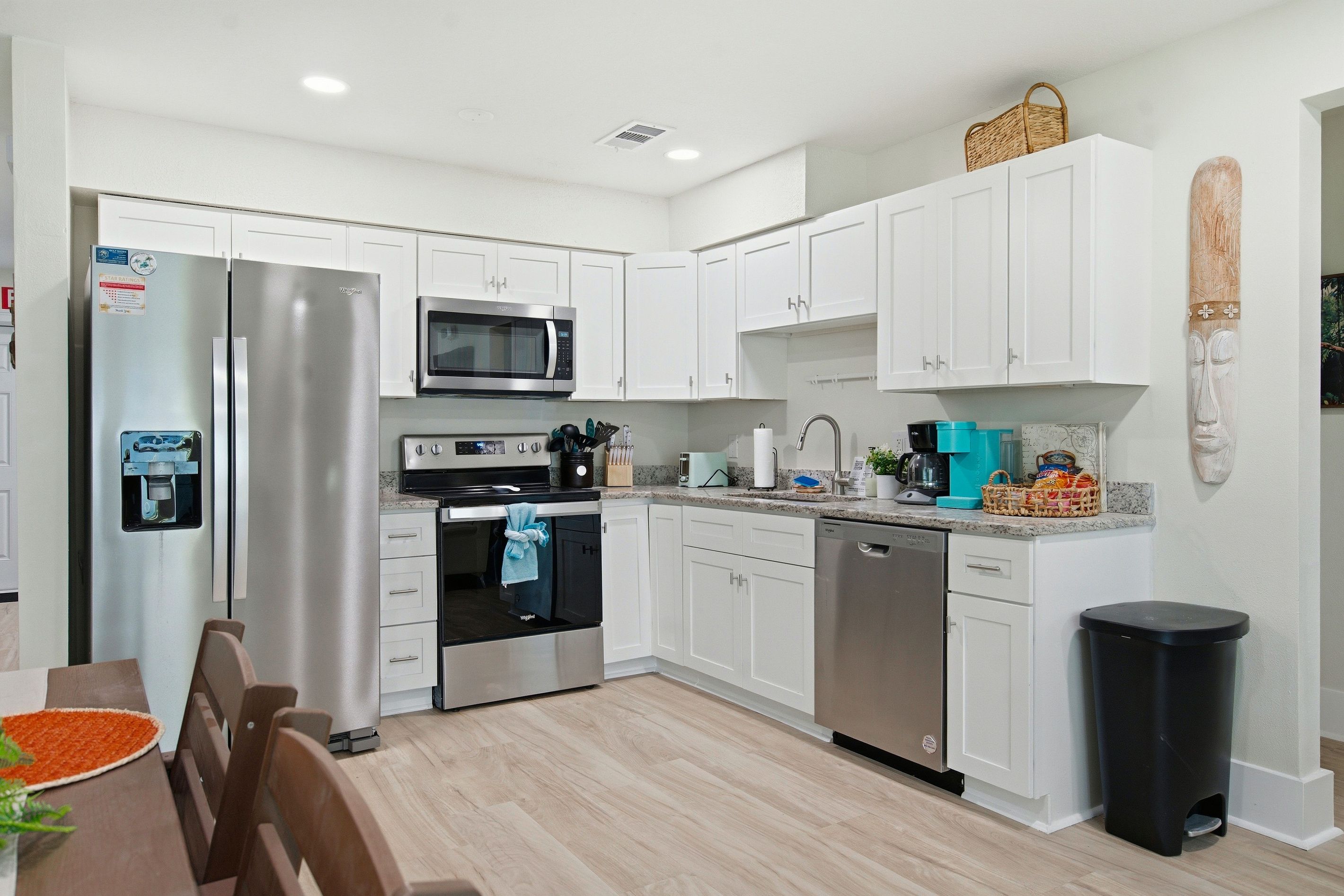 A modern kitchen with white cabinetry, stainless steel appliances, and a granite countertop.