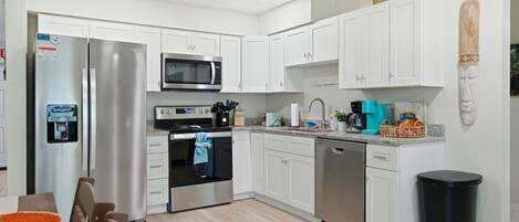 A modern kitchen with white cabinetry, stainless steel appliances, and a granite countertop.