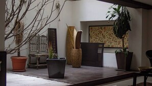 Ein Zimmer mit Holzboden, einem großen Fenster mit Blumenmuster, einer Topfpflanze und einer dekorativen Vase.