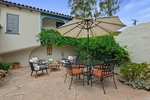 An outdoor patio with a round table, chairs, and a large umbrella.