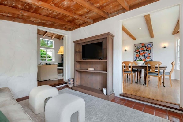 A living room with a TV, wooden furniture, and a dining area with a table and chairs. - Monte Sagrado (Montecito)