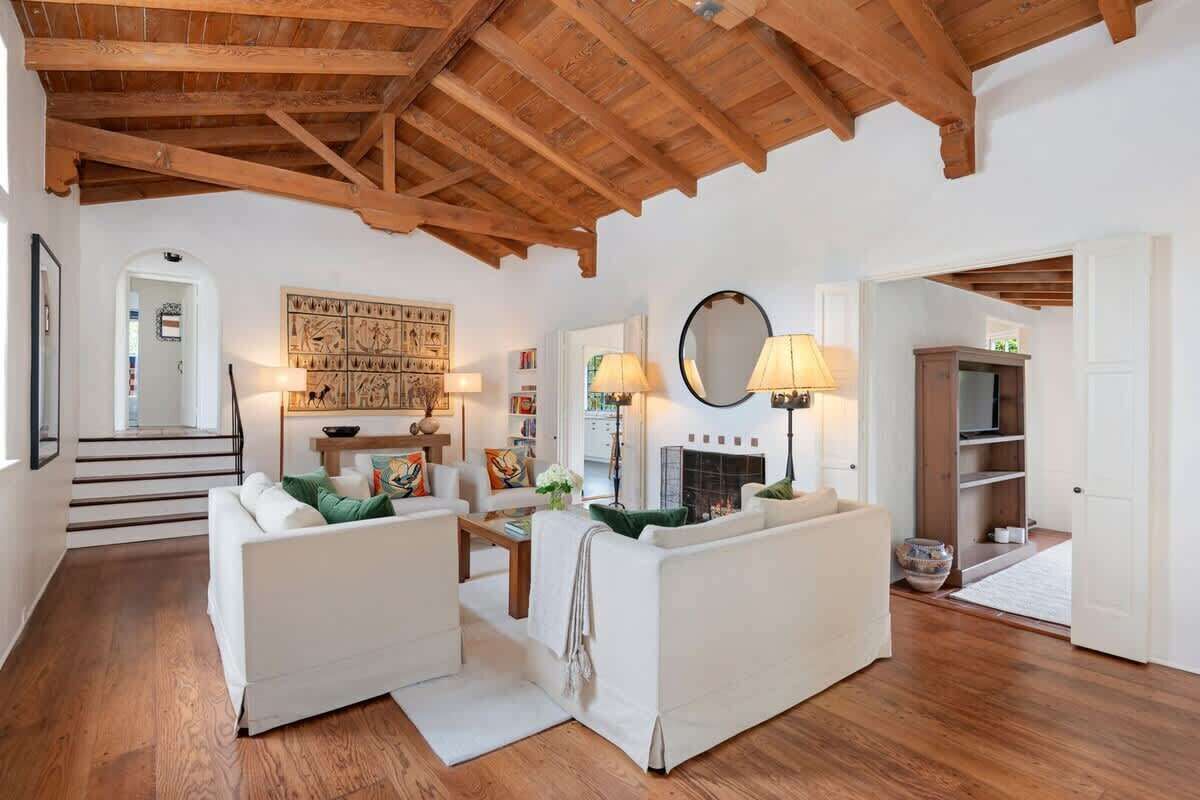 A living room with a fireplace, two sofas, a coffee table, and a staircase leading to another room.