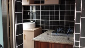 Una cucina con pareti rivestite di piastrelle bianche e nere, un piano di lavoro in legno e mobili beige.