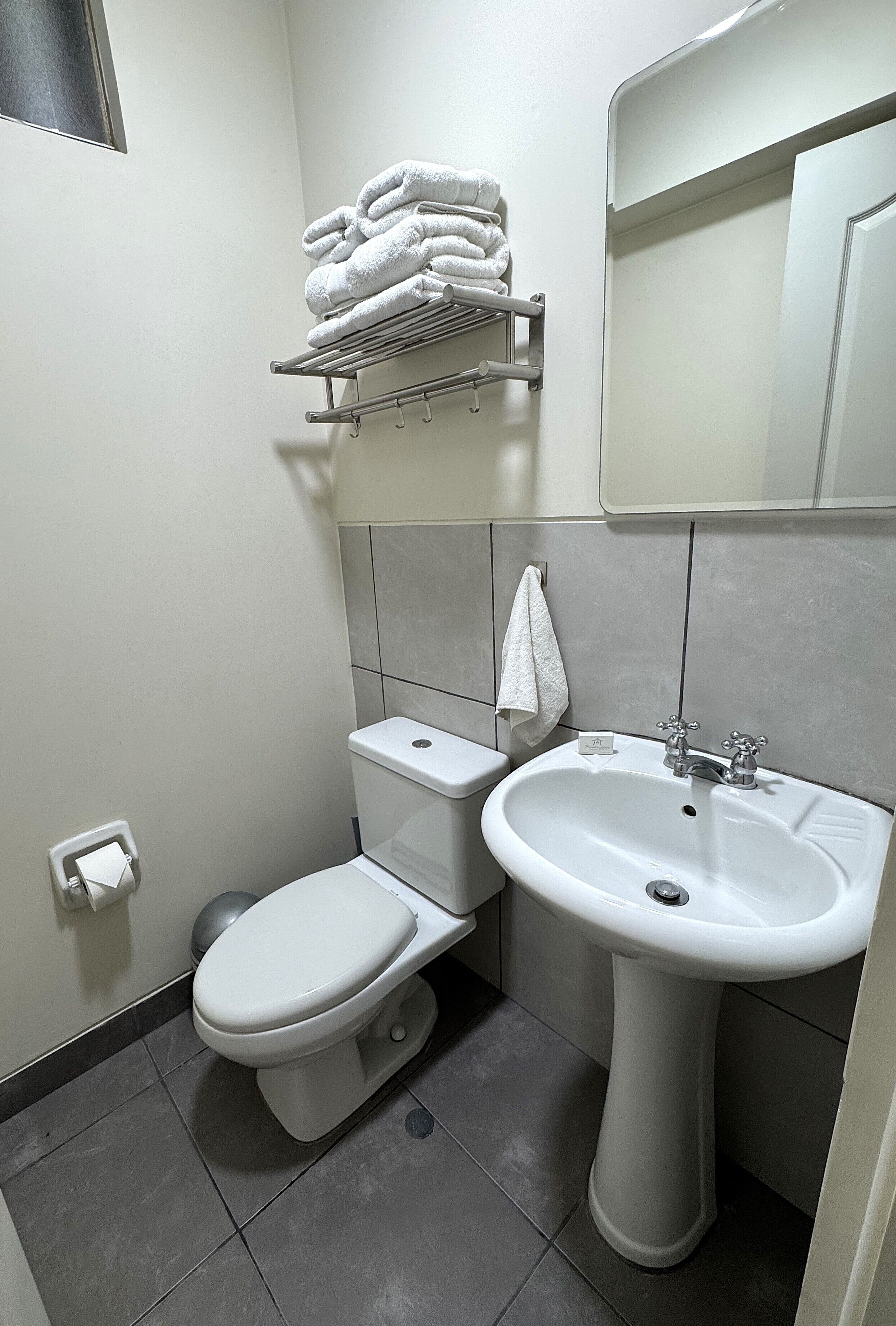 A small, clean bathroom with a toilet, sink, and towel rack.