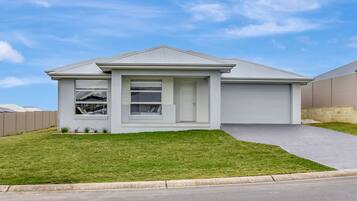 A single-story house with a garage, a front lawn, and a clear sky.
