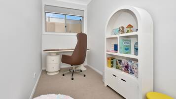 A child's room with a desk, chair, bookshelf, and a small stool.