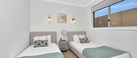 Une chambre avec deux lits, une fenêtre et des lampes fixées au mur.