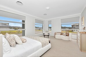 A modern bedroom with a large bed, a seating area, and a view of the outside.
