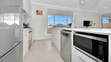 A modern kitchen with stainless steel appliances, a dishwasher, and a window providing a view of the outdoors.