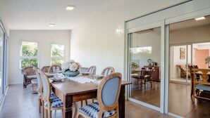 A dining area with a wooden table, chairs with patterned cushions, and a vase of flowers. - Quiet Site 2.7 km From the Beach of Rosa Stg2085 (Garopaba)