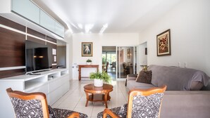 A modern living room with a flat-screen TV, a sofa, patterned chairs, a round wooden table with a plant, and artwork on the walls. - Quiet Site 2.7 km From the Beach of Rosa Stg2085 (Garopaba)