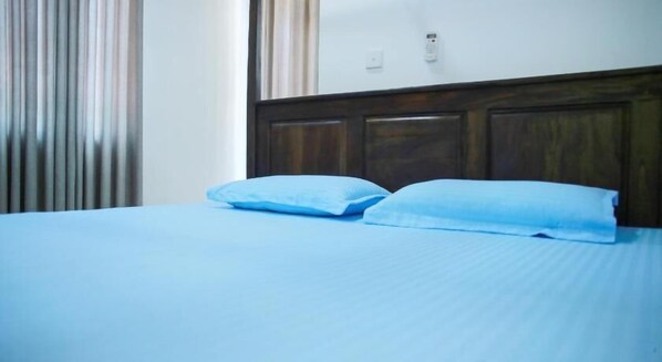 A bed with a wooden headboard and two pillows. - Amible guest home (Mirissa)