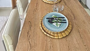 Une table de salle à manger en bois, mise avec des assiettes, des couverts et des verres.