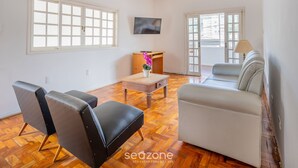 Un salon avec un canapé, des fauteuils, une table basse et un téléviseur.