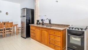 Une cuisine avec des meubles en bois, un réfrigérateur en acier inoxydable, une cuisinière à gaz et une machine à café.