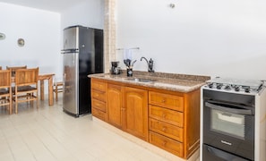 Una cocina con armarios de madera, un refrigerador de acero inoxidable, una estufa a gas y una cafetera.