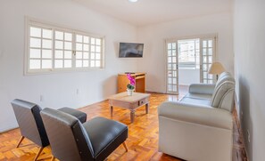 Un salon avec un canapé, des fauteuils, une table basse et un téléviseur.