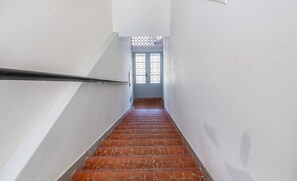 Una escalera con baldosas rojas estampadas que conduce a una puerta con diseño de celosía.