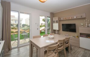 Une cuisine moderne avec un coin repas, un téléviseur et une vue sur le jardin.